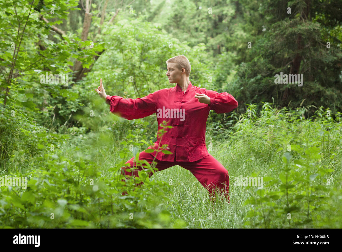 Concentrated woman practicing Tai Chi amidst trees on field Stock Photo