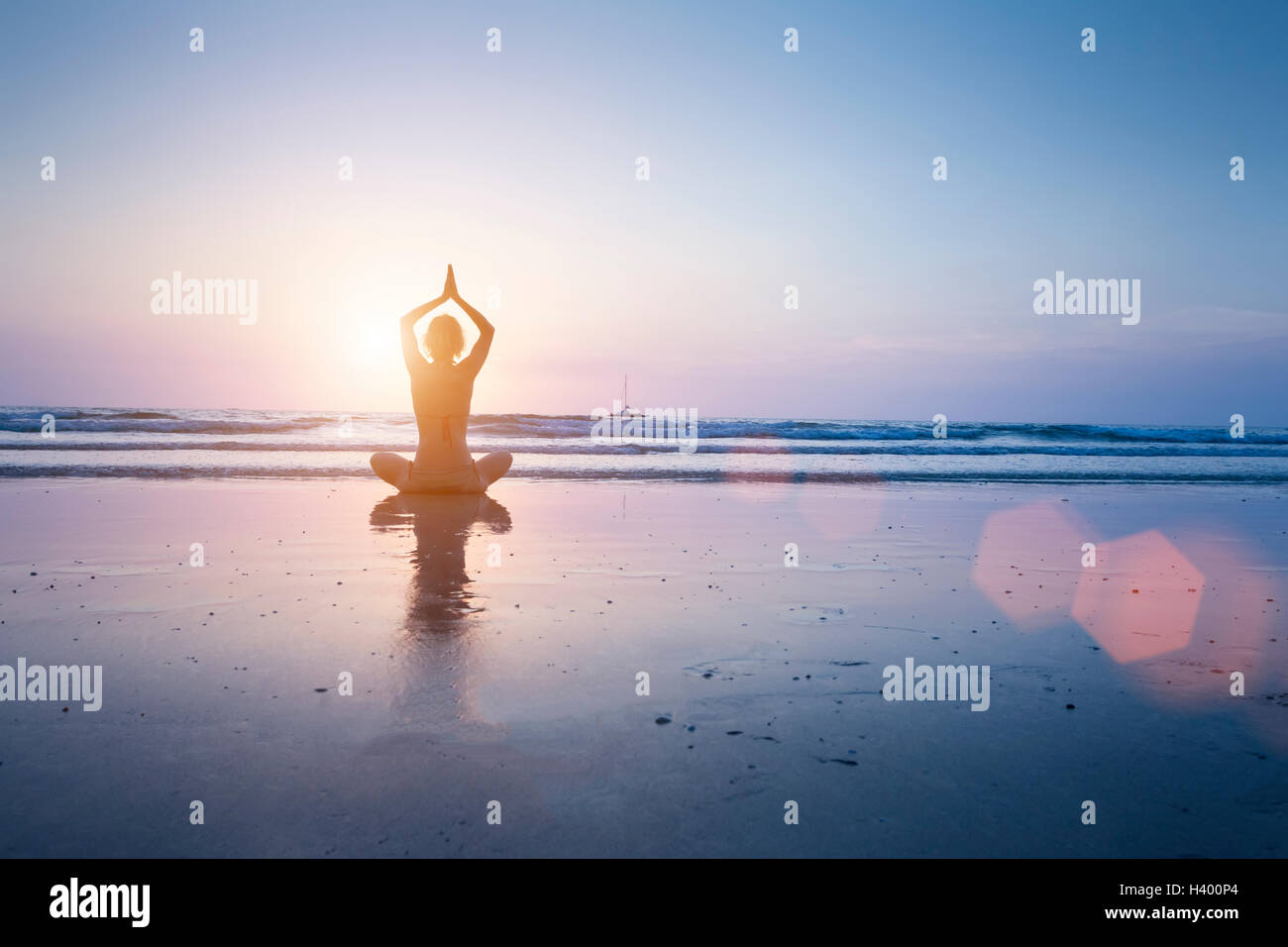 Happy woman enjoying healthy yoga practice at sunrise on a beautiful sandy beach in Koh Chang, Thailand Stock Photo