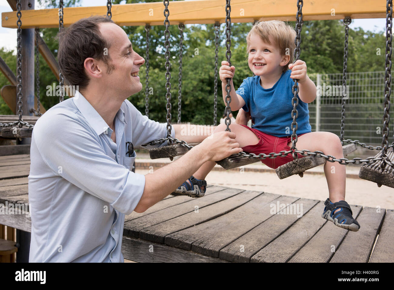 Smiling father looking at son playing on jungle gym Stock Photo