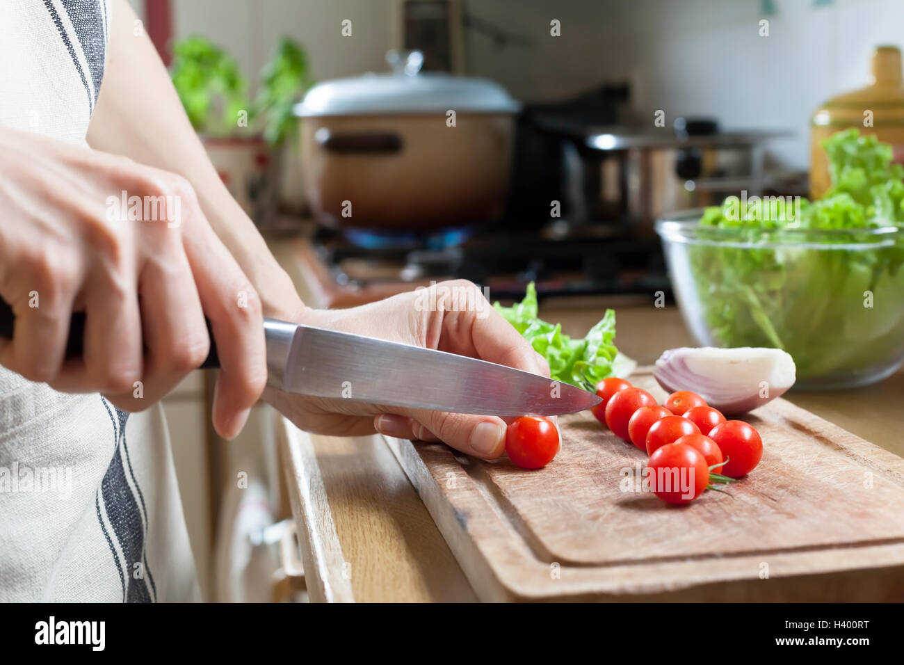 Woman cutting tomatoes to prepare meal at home Stock Photo