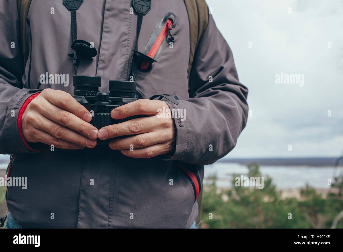 Midsection of man with binoculars against sky Stock Photo
