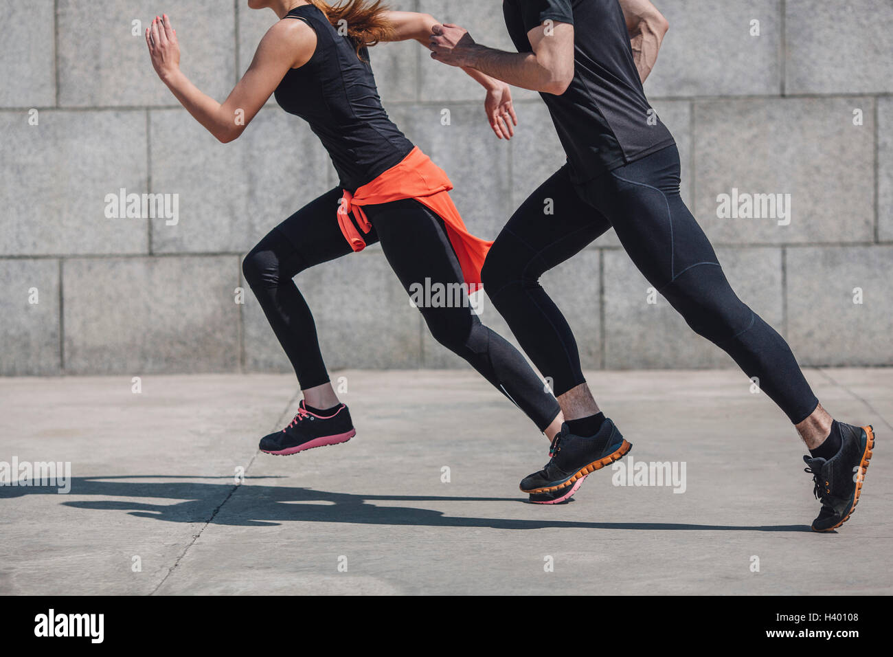 Low section of people jogging on sidewalk by wall Stock Photo