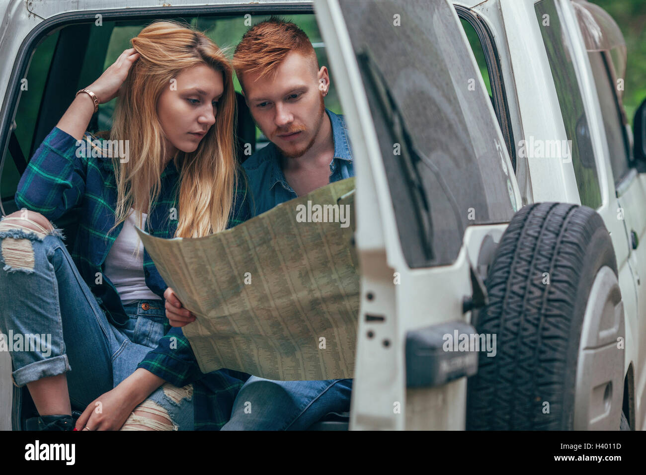 Couple analyzing map while sitting in off-road vehicle at forest Stock Photo