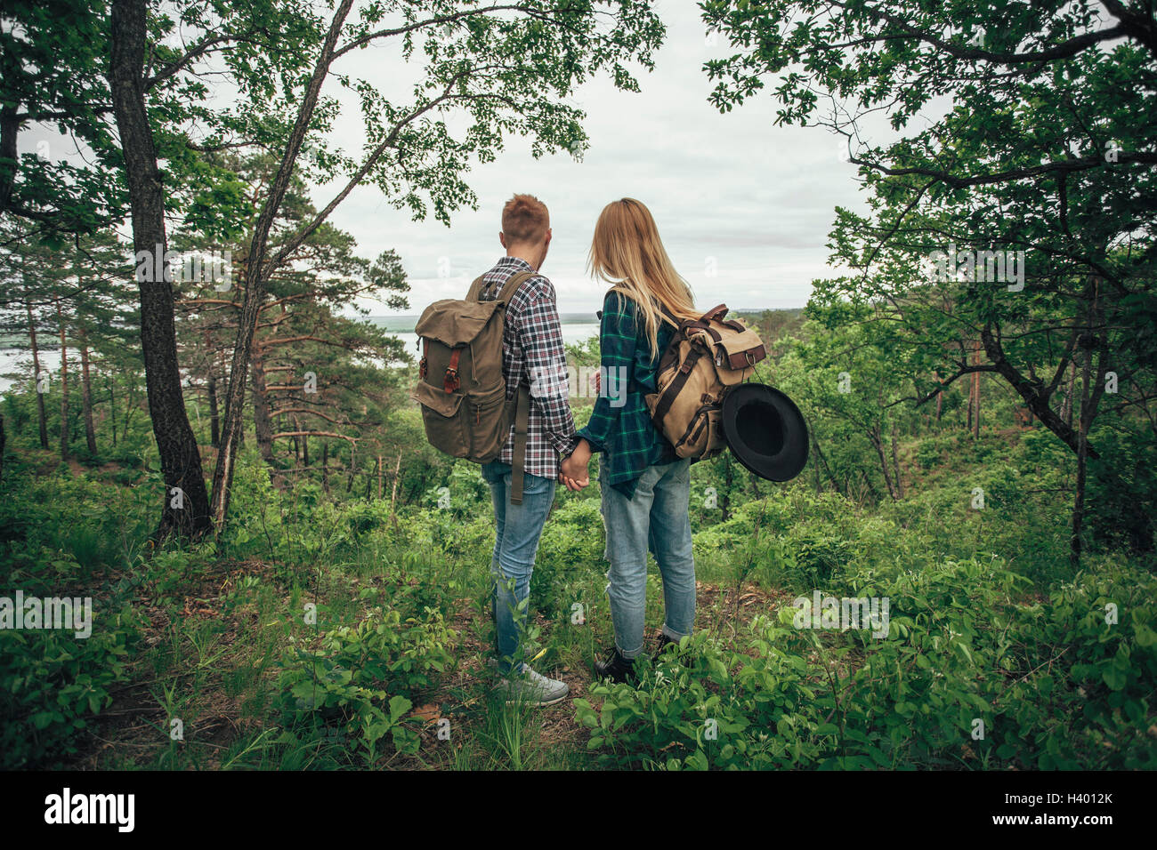 Rear view of couple holding hands while hiking at forest Stock Photo ...