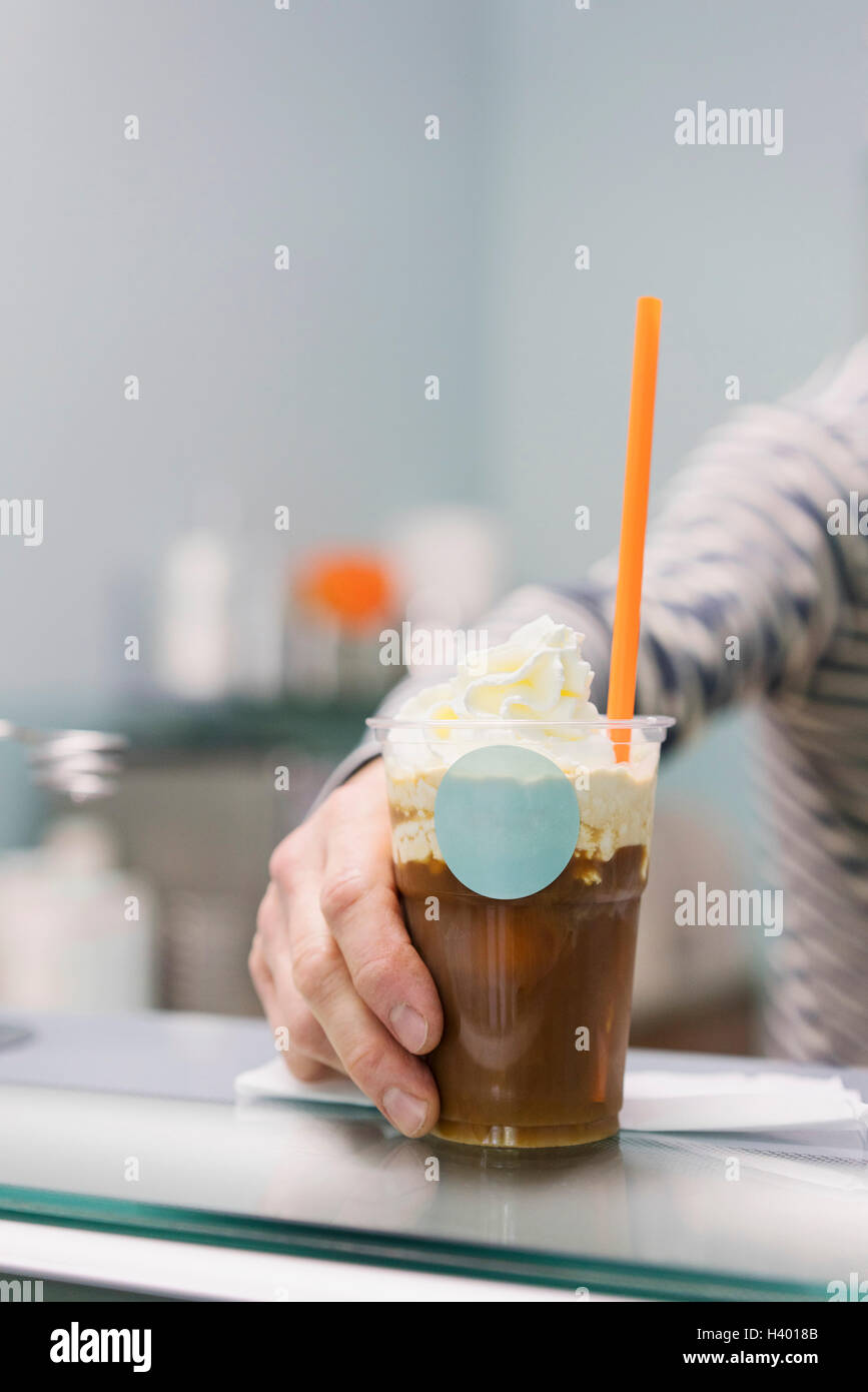 Detail of hand holding iced coffee on counter Stock Photo