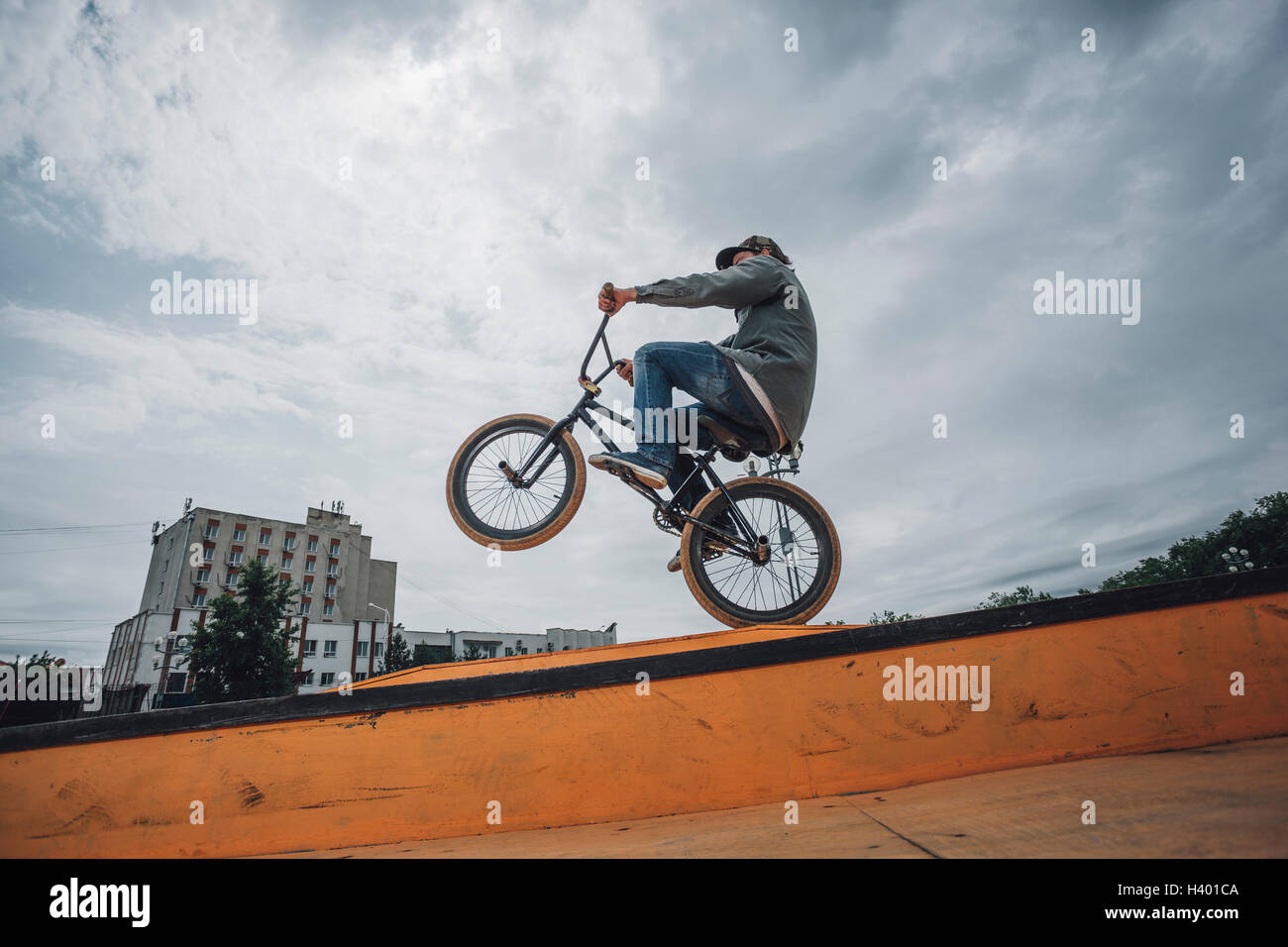 Low angle view of teenage boy performing stunt on ramp against cloudy ...