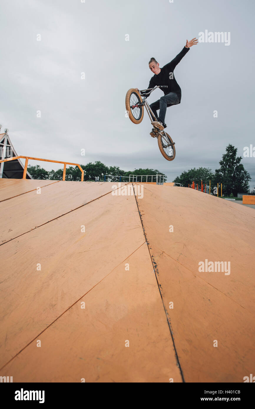 Teenager performing stunt on BMX bicycle at skateboard park Stock Photo