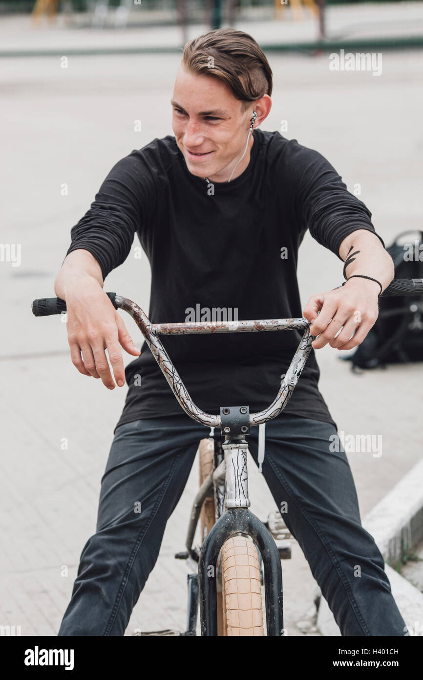 Smiling teenager sitting on bicycle at skateboard park Stock Photo Alamy
