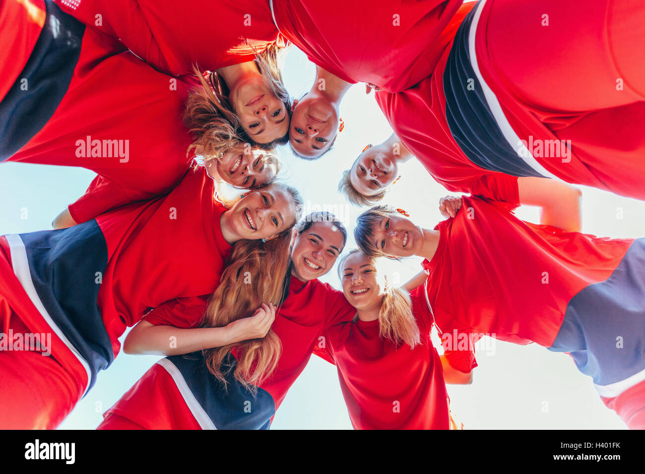 Directly below shot of soccer players huddling against clear sky Stock Photo