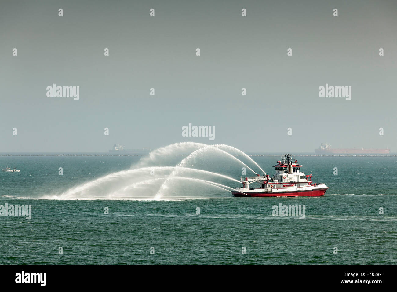Fire boat spraying water into sea against sky Stock Photo Alamy