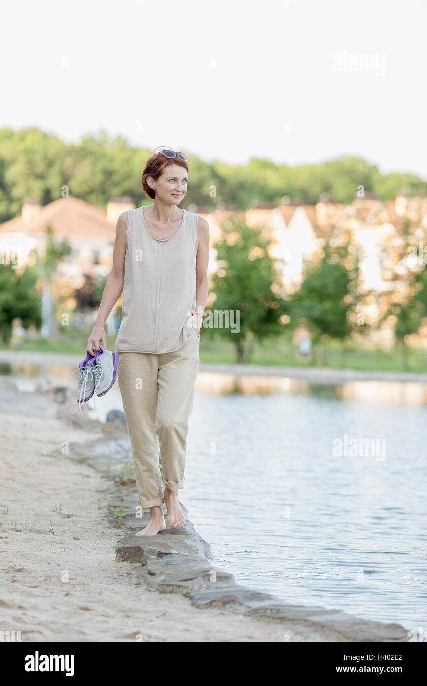 Woman walking on lakeshore against clear sky Stock Photo