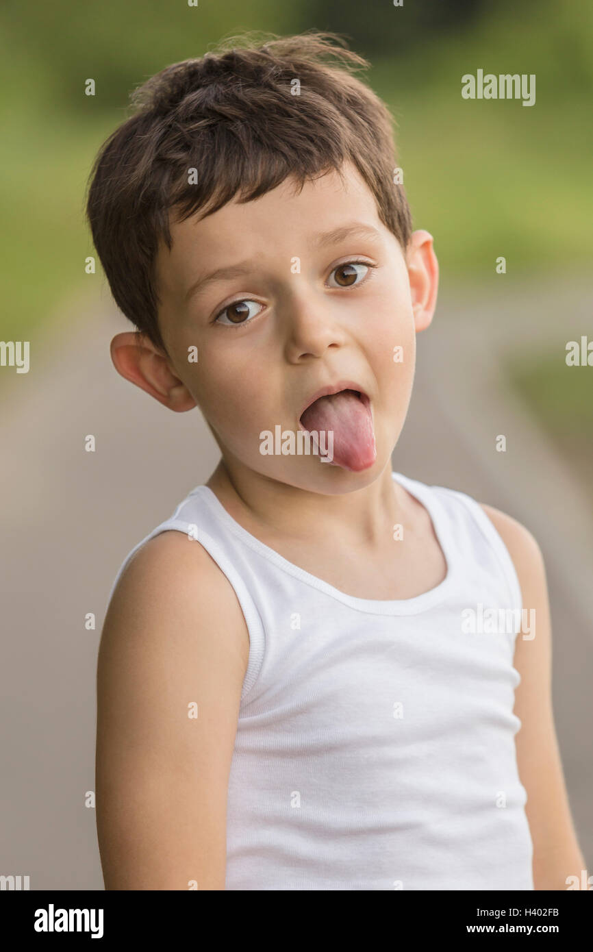 Portrait of boy sticking out tongue while standing at park Stock Photo