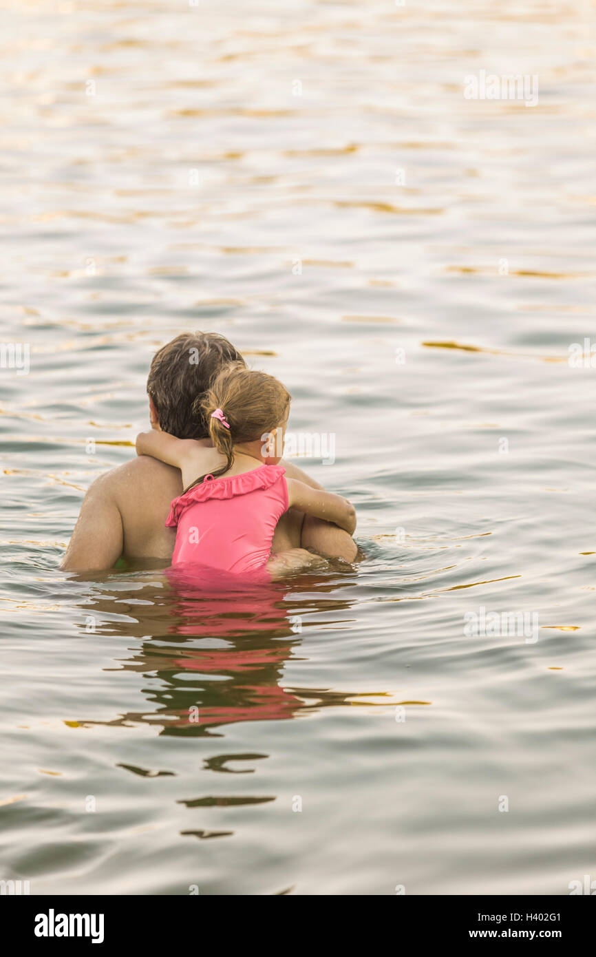 Rear view of father piggybacking daughter in lake Stock Photo
