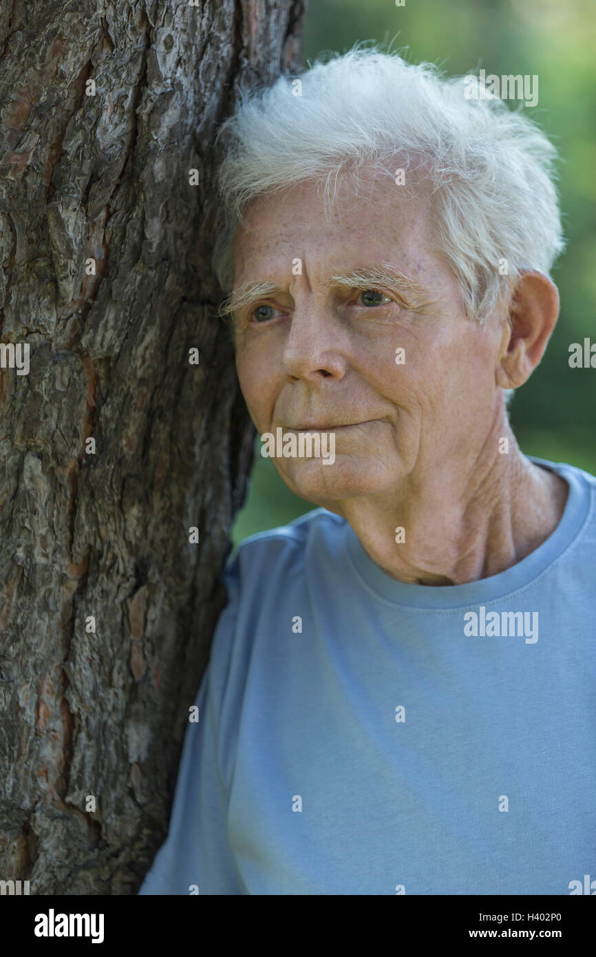 Close-up of thoughtful senior adult standing by tree Stock Photo