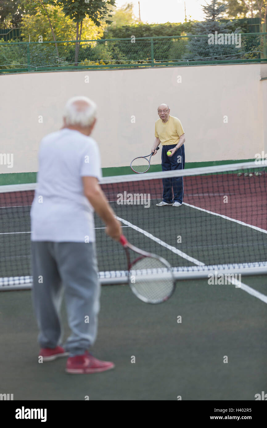 Senior men playing tennis at court Stock Photo