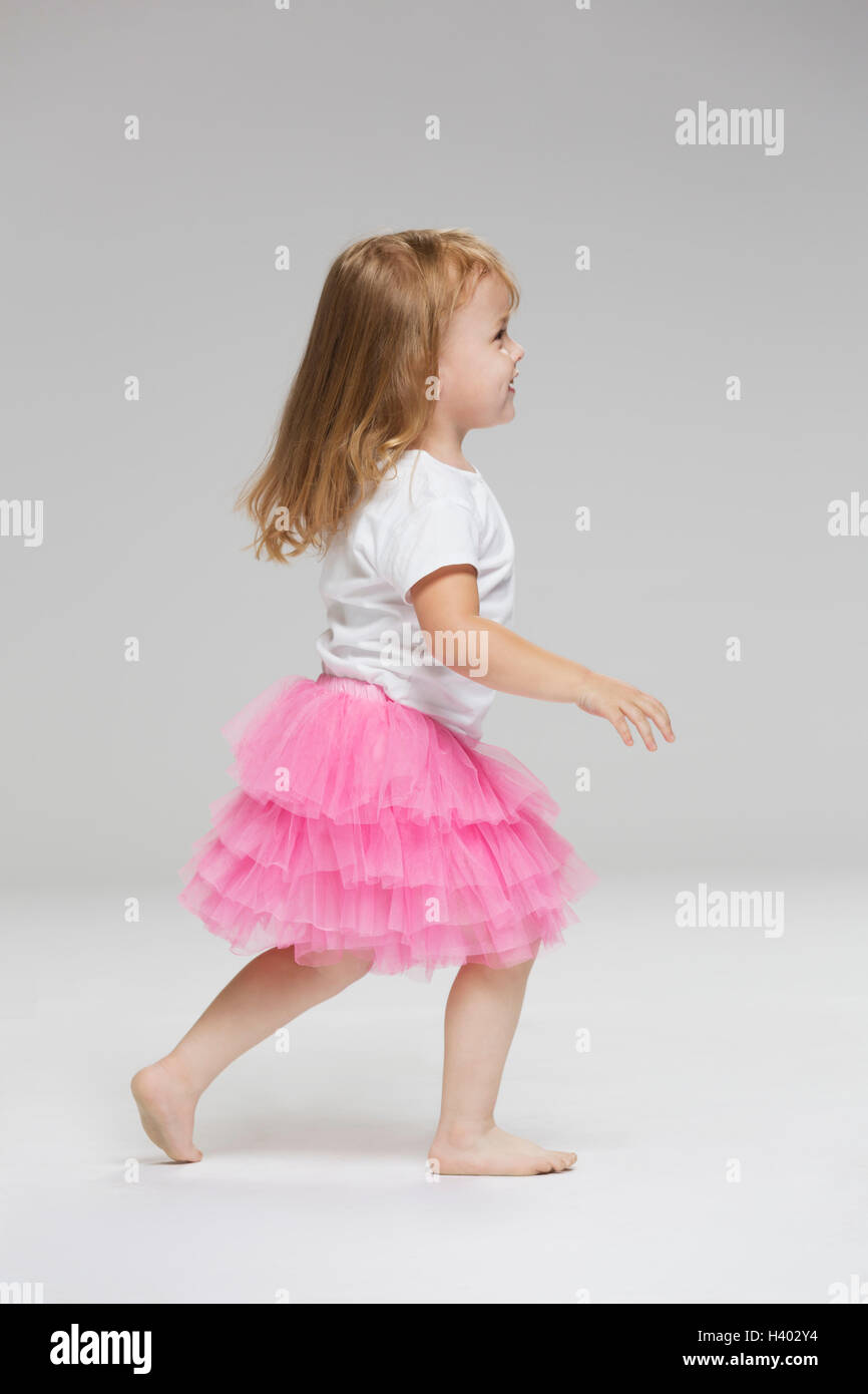 Side view of girl wearing tutu playing against gray background Stock Photo