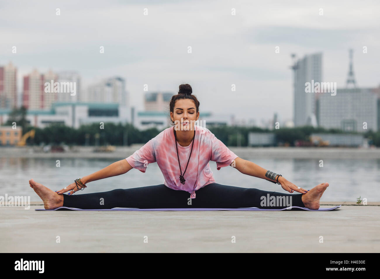Beautiful woman practicing yoga against river in city Stock Photo