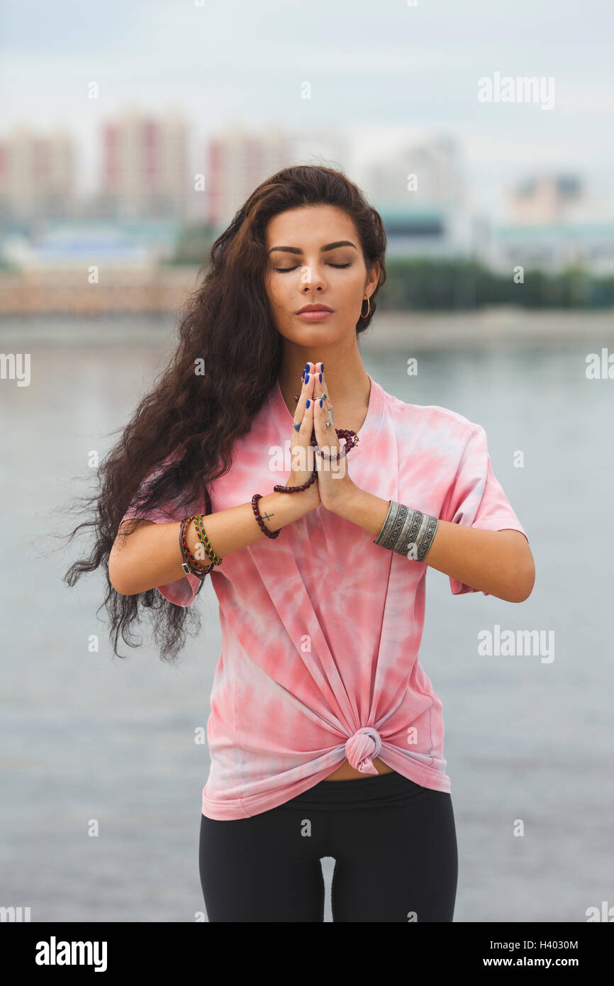 Young woman with closed eyes practicing yoga in prayer position against river Stock Photo