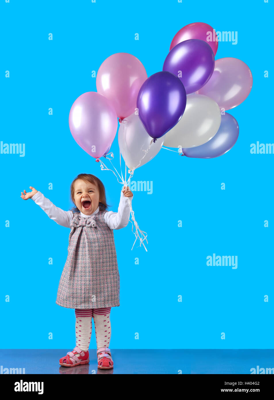 Happy little girl with balloons on a blue background Stock Photo - Alamy