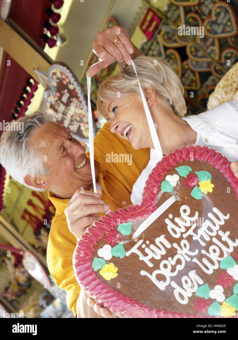 Spring feast, Senior couple, happy, declaration love, gingerbread heart, eye contact, half portrait, fair, public festival, feast, amusement park, senior citizens, couple, falls in love, love, happy, joy life, initiative, cheerfulness, joy, fit, agile, fu Stock Photo