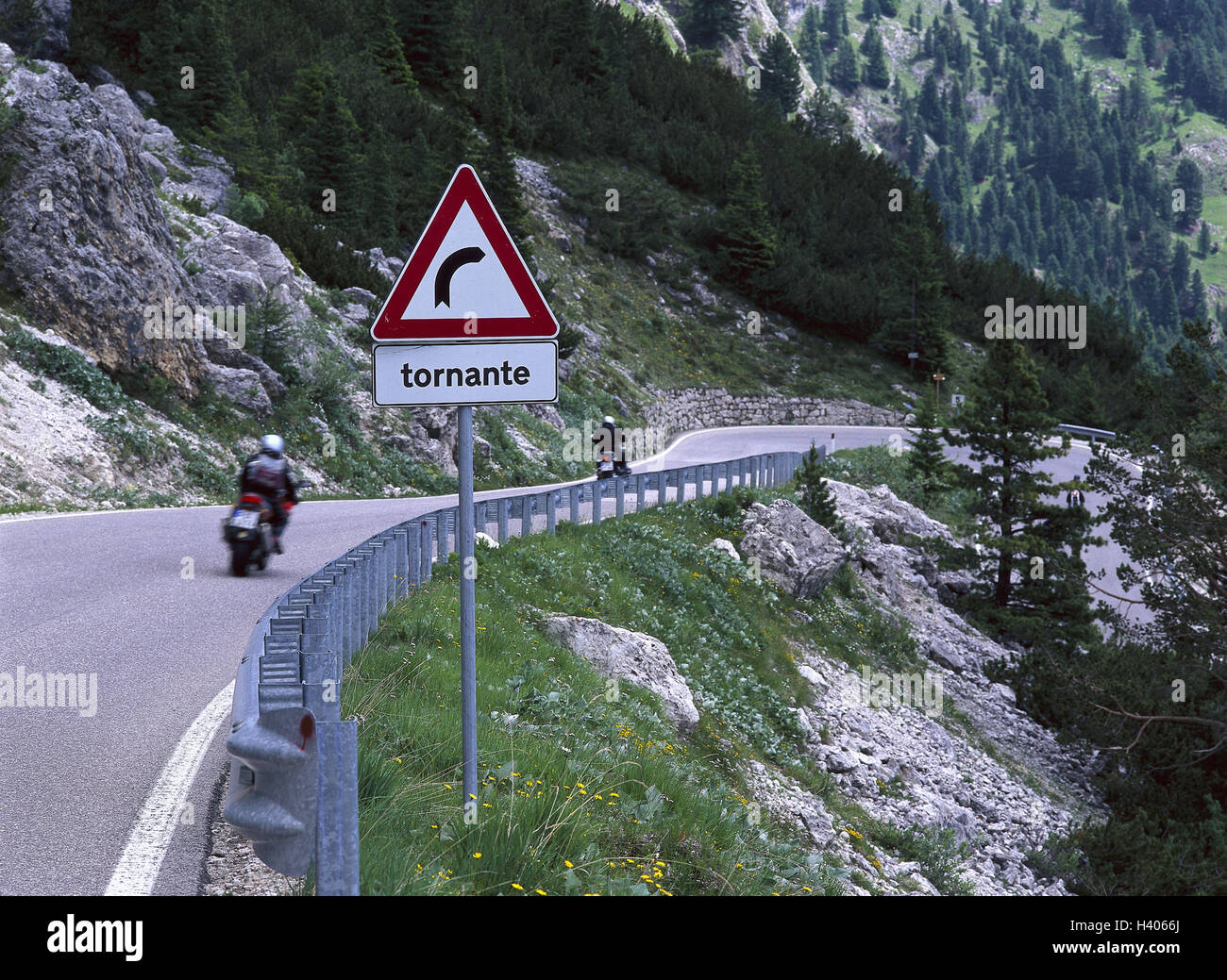 Italy, South Tyrol, mountain landscape, Sellajoch, mountain pass, sign, bend, 'Tornante', motorcyclist, Europe, alps, dolomites, mountains, street, mountain road, pass, guardrail, road sign, traffic sign, sign, danger sign, danger, tip, in Italian, Turning, Bend, Legal bend, bendy, motorcycles, traffic, travelling, excursion, motorcycle driving Stock Photo