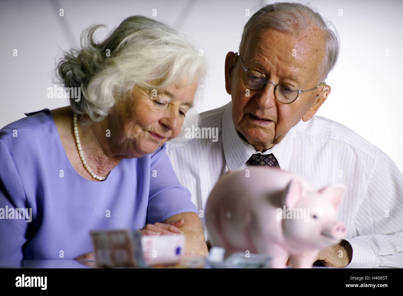 money, couple of seniors, portrait, piggybank, severe, counting Stock Photo