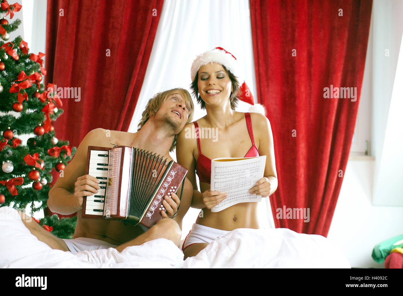 Christmas, bed, couple, happy, carols, sings, accordion, bedrooms play, Christmas tree, woman, Santa's hat, cap, partnership, lovers, love, affection, Privately, leisure time, togetherness, cosiness, falls in love, there, smile, fun, songs, songbook, concertina, together, cheerfulness Stock Photo