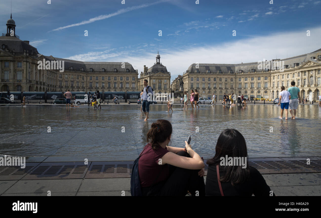 People enjoy the Miroir d'Eau (a large reflecting pool) in front of the Place de la Bourse in Bordeaux, France Stock Photo