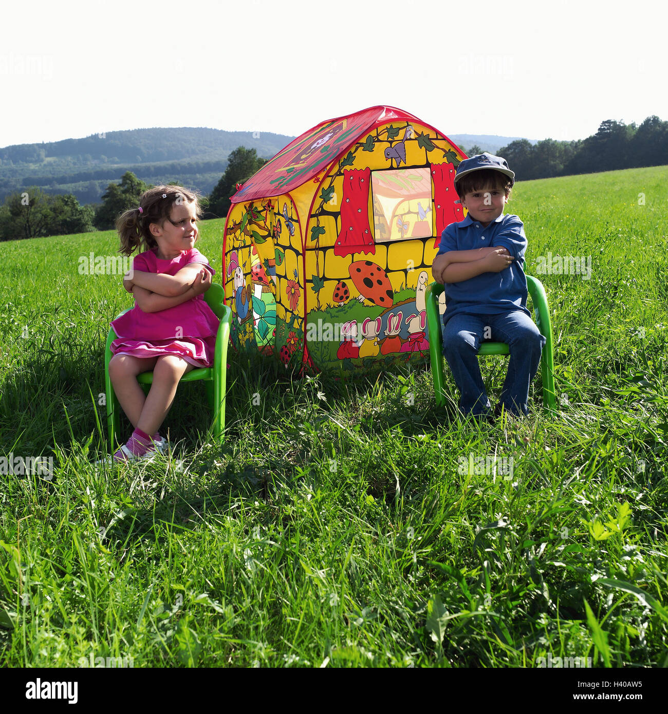 Meadow, children-game house, children, sit, chairs, arms, crosses, 4 years, siblings, boy, girl, friends, sulk, play fight, difference, distance, distance, childhood, tent, house, brightly, colourfully, icon, own home, security, security, Eigenheim-Kredit Stock Photo
