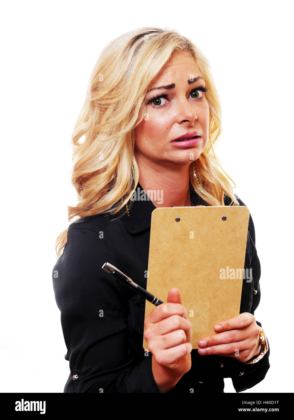 A worried blond business woman is holding a clipboard and looking into the camera. Stock Photo