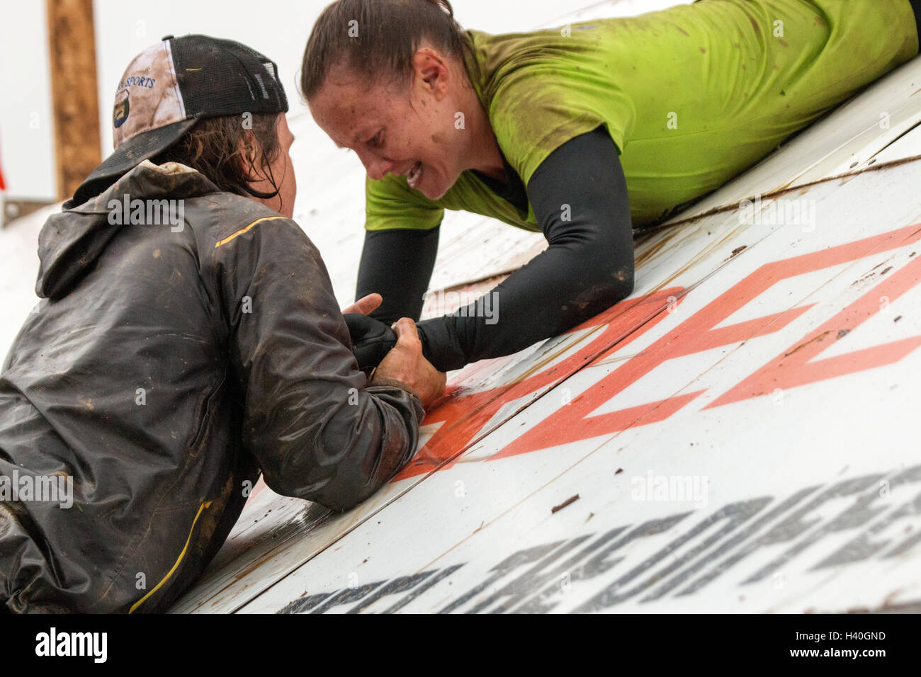 Two Tough Mudder competitors on an angle wall Pyramid Scheme Stock Photo