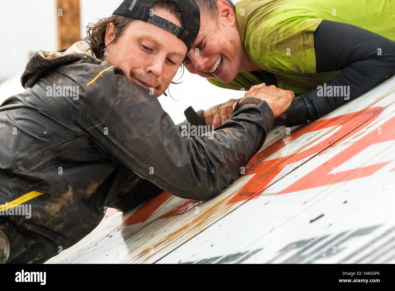 Two Tough Mudder competitors on an angle wall Stock Photo
