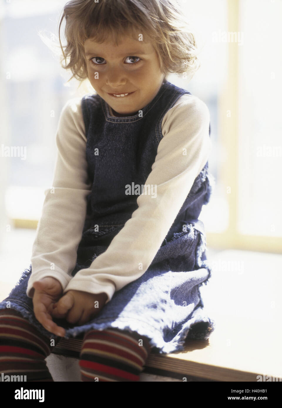 Girls, shyly, smile, windowsill sit, child, 5 - 7 years, blond, jeans dress, dress, sock trousers, curled, leisure time, childhood, happy, shyness, curled Stock Photo