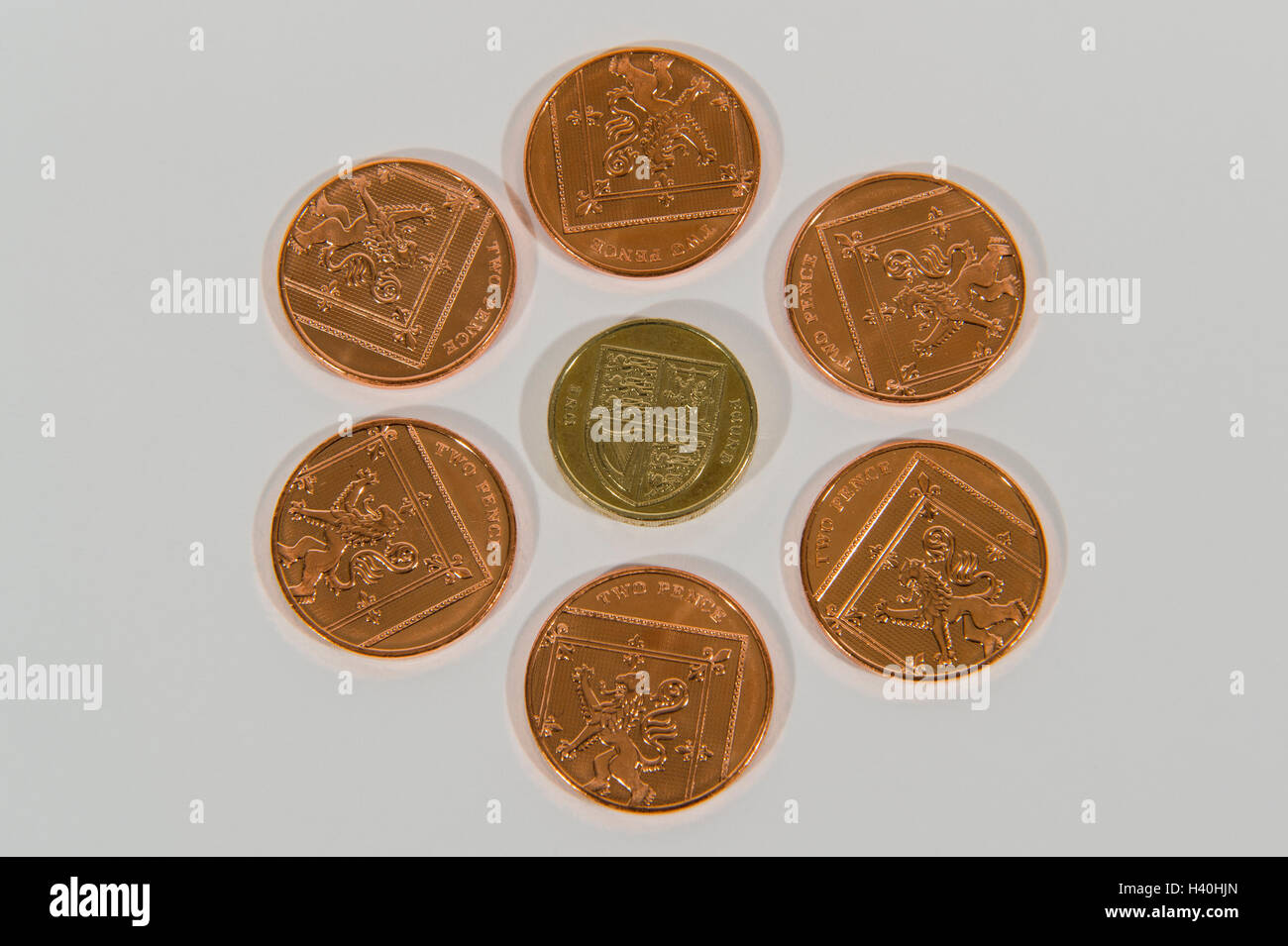 Close-up detail of money - current UK sterling coins in 2 denominations, copper and silver with 2p pieces around a single £1. Stock Photo