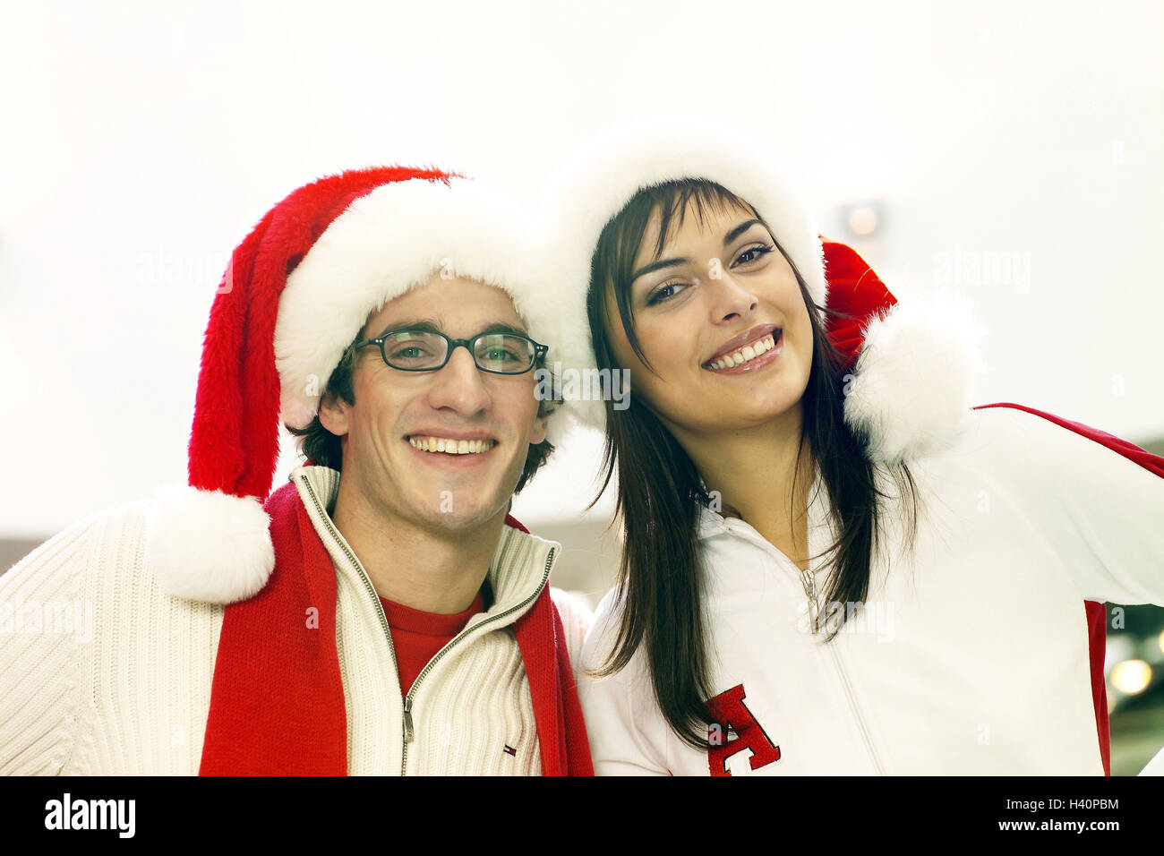 Shopping centre, couple, young, happy, Santa's hats, portrait, yule tide, Christmas period, department store, cheerfulness, joy, together, embrace, affection, happy, falls in love, love, partnership, friendship, glasses, wearers glasses, caps Stock Photo