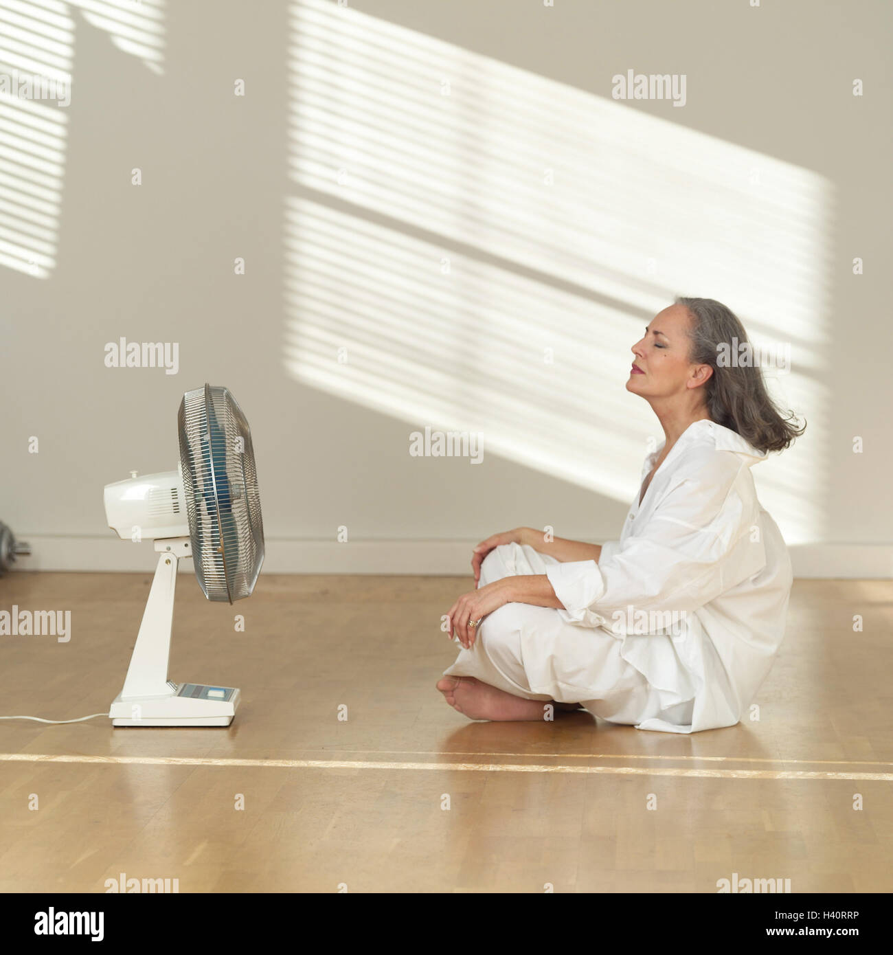 Living space, sit blank, senior, floor, fan, draught, enjoy, at the side woman, 50-60 years, Best of all Age, long-haired, grey-haired, leisurewear, Schneider's seat, heat, heat, hotly, détente, rest, cooling, cooling, air, flat, inside, at home Stock Photo