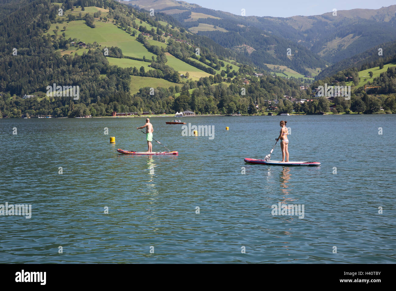 A man and woman paddle boarding on lake Zell am See in Austria Stock