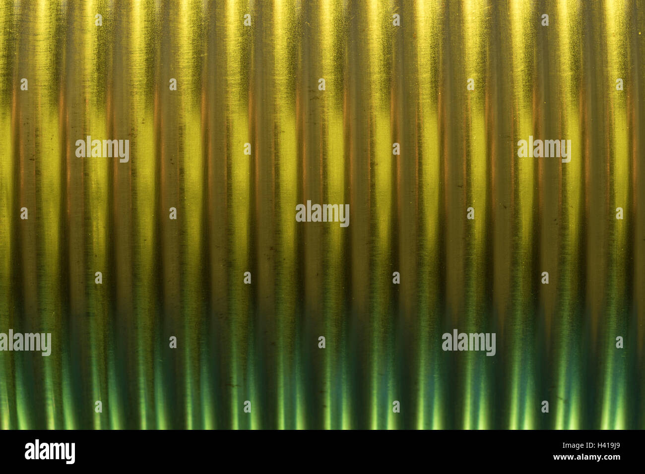 Abstract image of metal / tin can strengthening ridges (actually a baked bean tin) illuminated with yellow-green colored light. Abstract steel can. Stock Photo