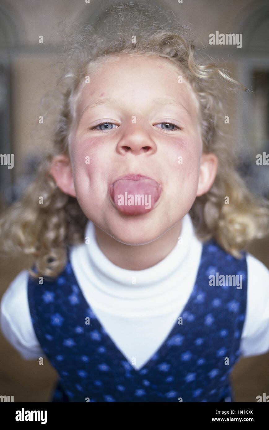 Girls, blond, tongue point, portrait, very close, inside, child, 6 years, long-haired, curls, fun, provocation, insults, bad habit, naughtily, impolitely, cheeky, perky, cheeky, education, tongue stick out Stock Photo