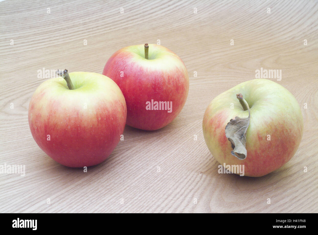 wooden table, apples, Braeburn, three, completely, table, wooden board, wooden surface, fruits, fruit, pomes, Malus, apple sort, ripe, eat, nutrition healthy, rich in vitamins, Still life, product photography Stock Photo