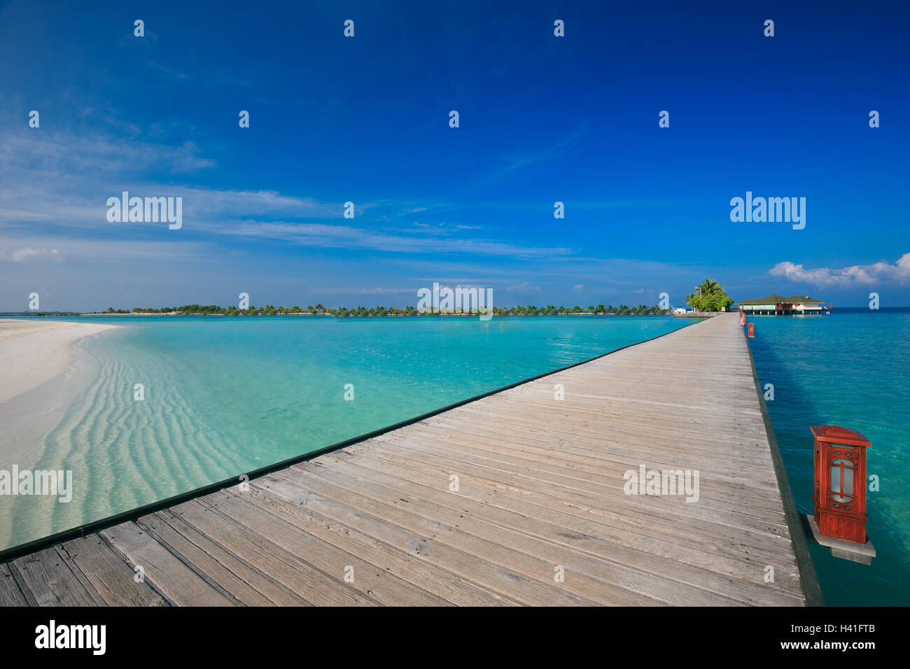 Bridge leading to overwater bungalow in blue lagoon around tropical Maldives island Stock Photo