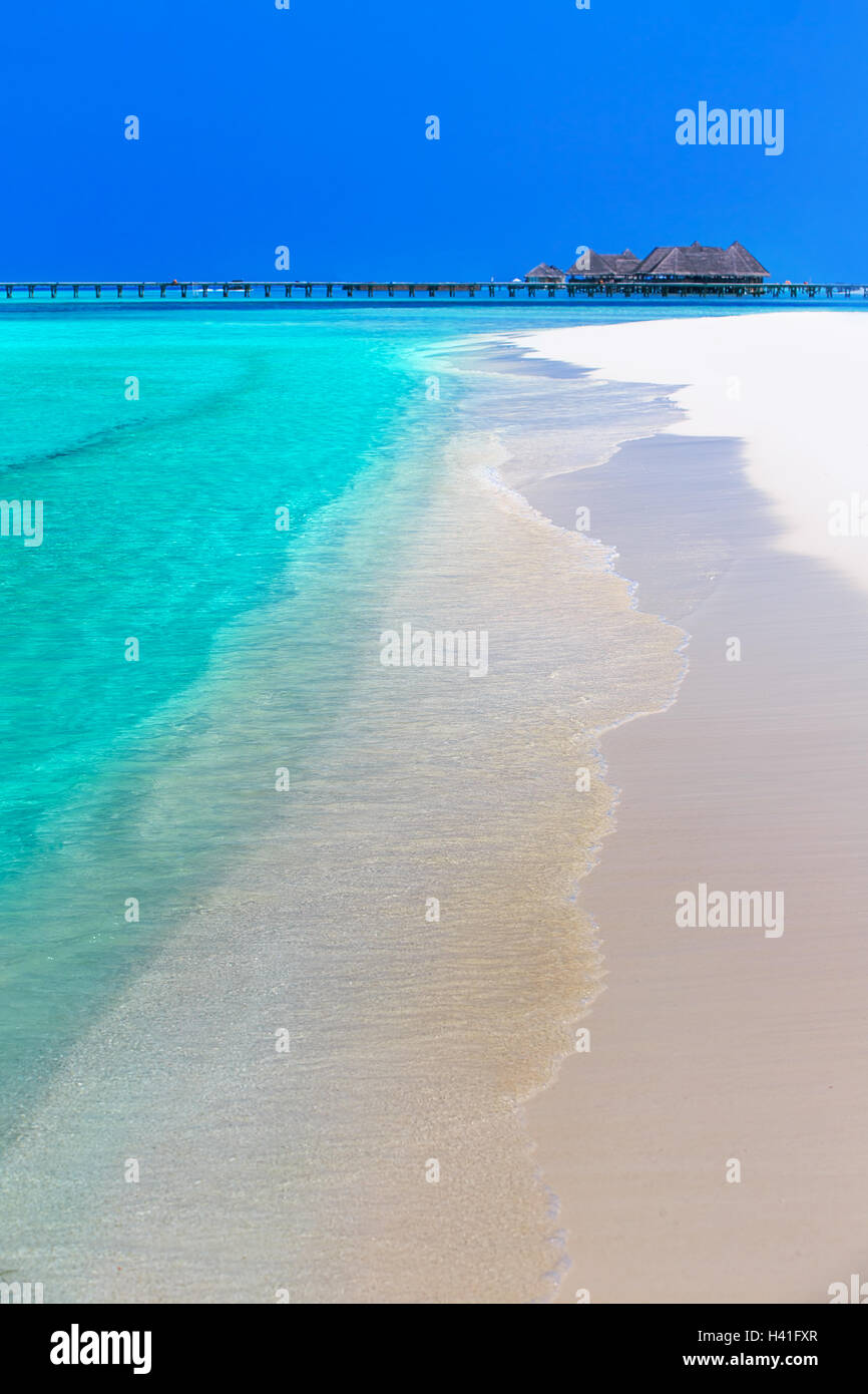 Tropical island with sandy beach, overwater bungalows and tourquise clear water Stock Photo