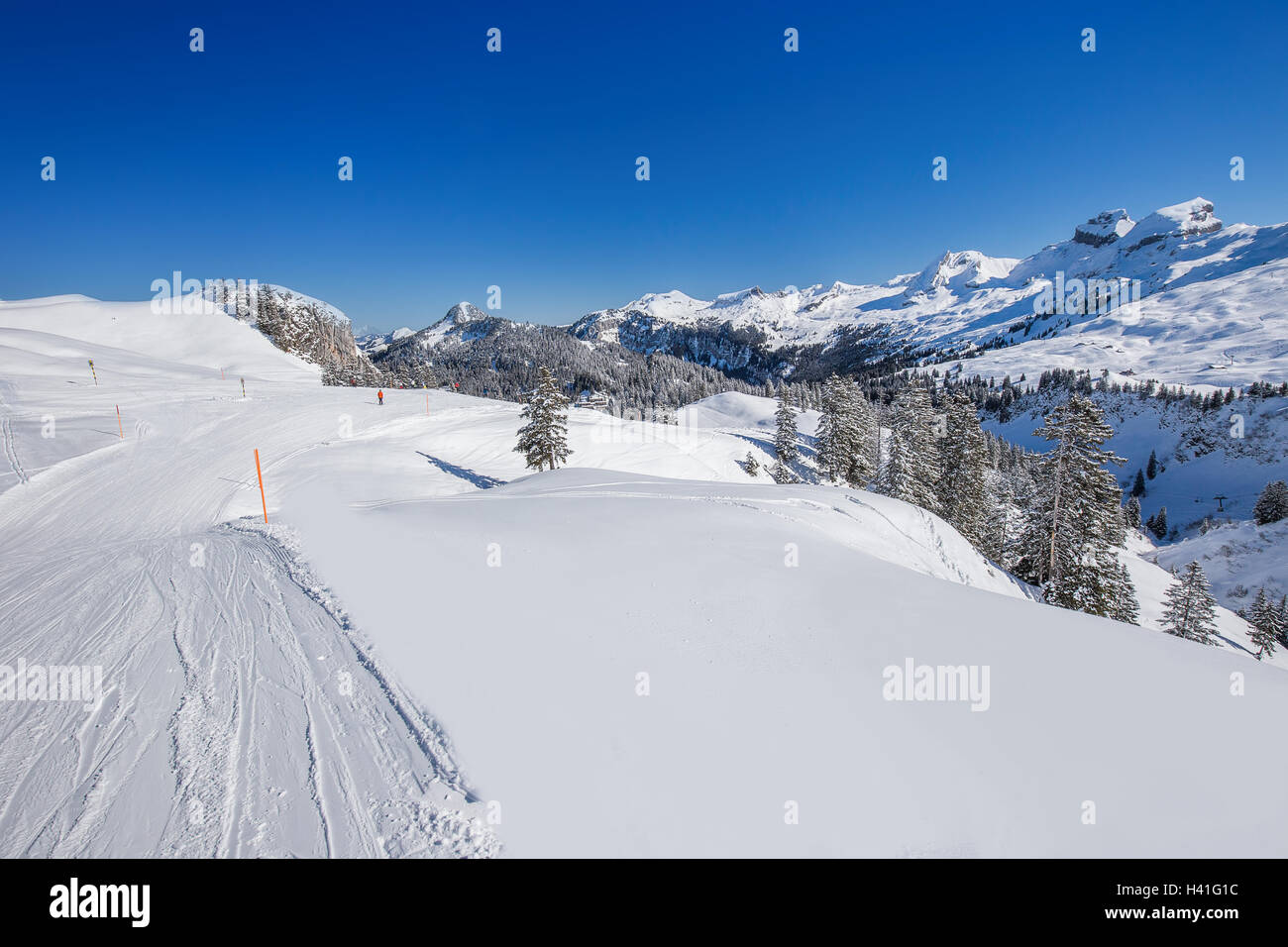 View ti Skiers on the ski slopes and Swiss Alps covered by fresh new snow seen from Hoch-Ybrig ski resort, Central Switzerland Stock Photo