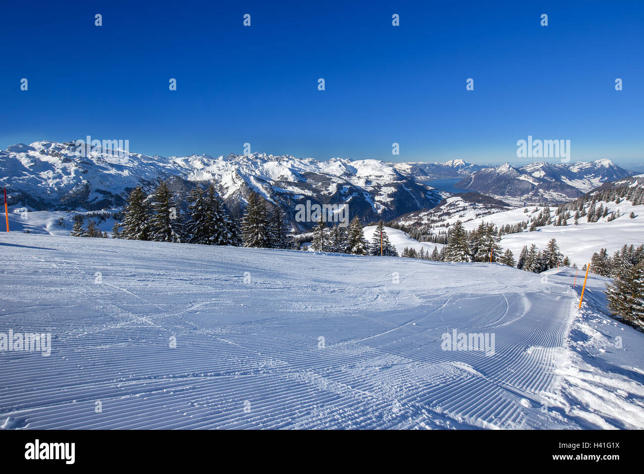 Ski slopes, Lake Lucerne and Swiss Alps covered by fresh new snow seen from the Spirstock peak in Hoch-Ybrig ski resort Stock Photo