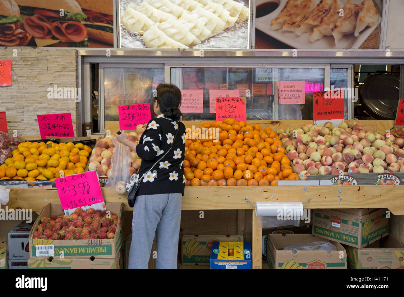 An anonymous Asian woman shopping for fruit at Happy Fruit in Chinatown, downtown Flushing, New York City. Stock Photo