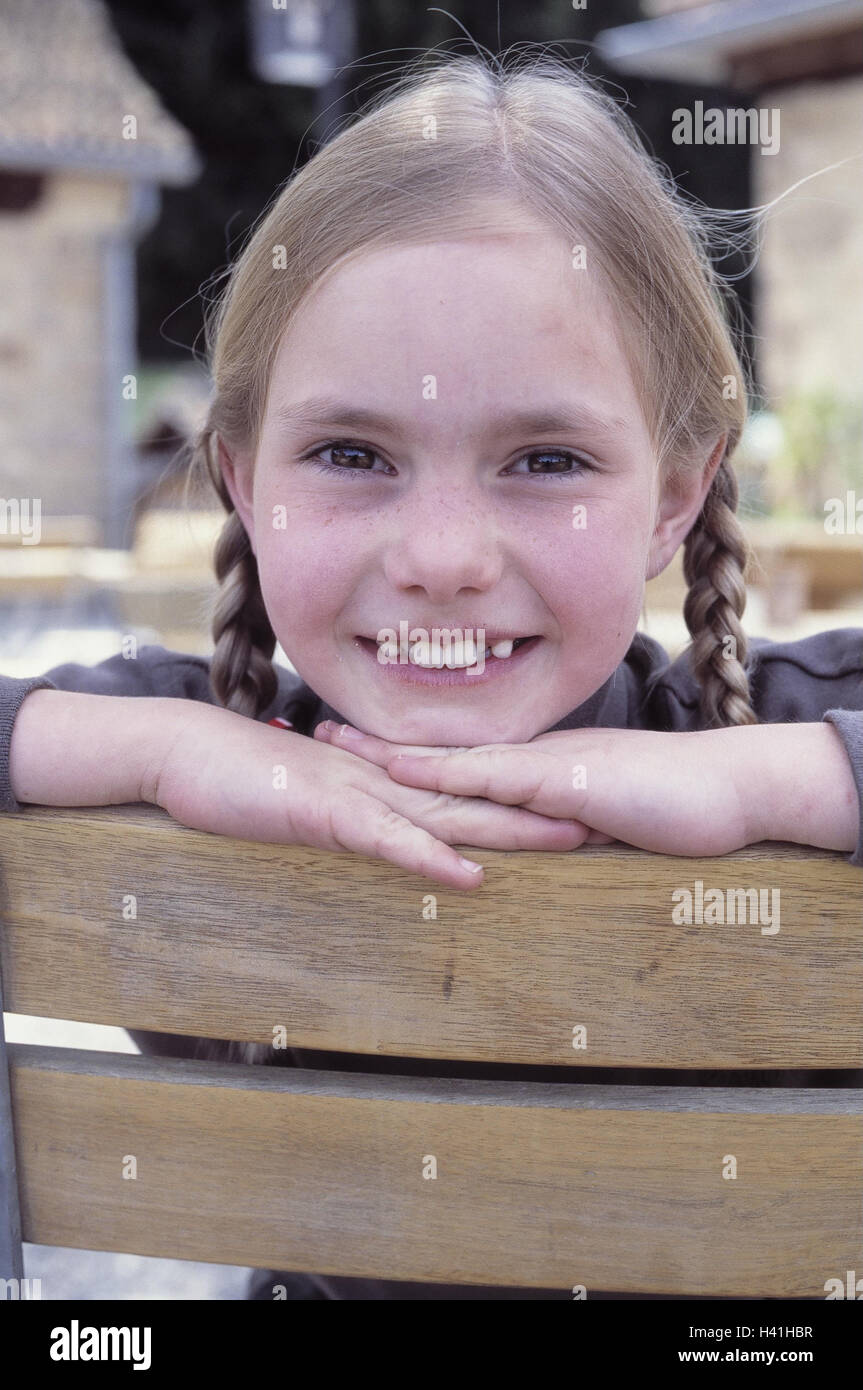 Fence, detail, girl, head, rest on, there, smile, portrait, outside, child, 8 years, expression, contently, satisfaction, happy, tooth gaps, second dentitions, long-haired, plaits, hairstyle, wooden fence, paling, wooden bars Stock Photo