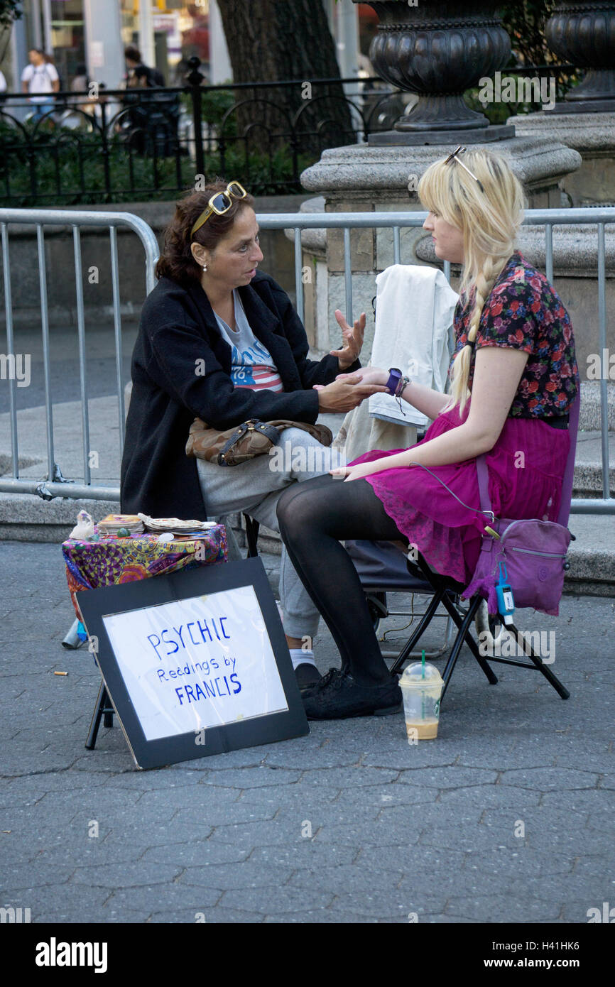 A woman giving a psychic reading palm reading in Union Square Park in Manhattan, New York City. Stock Photo