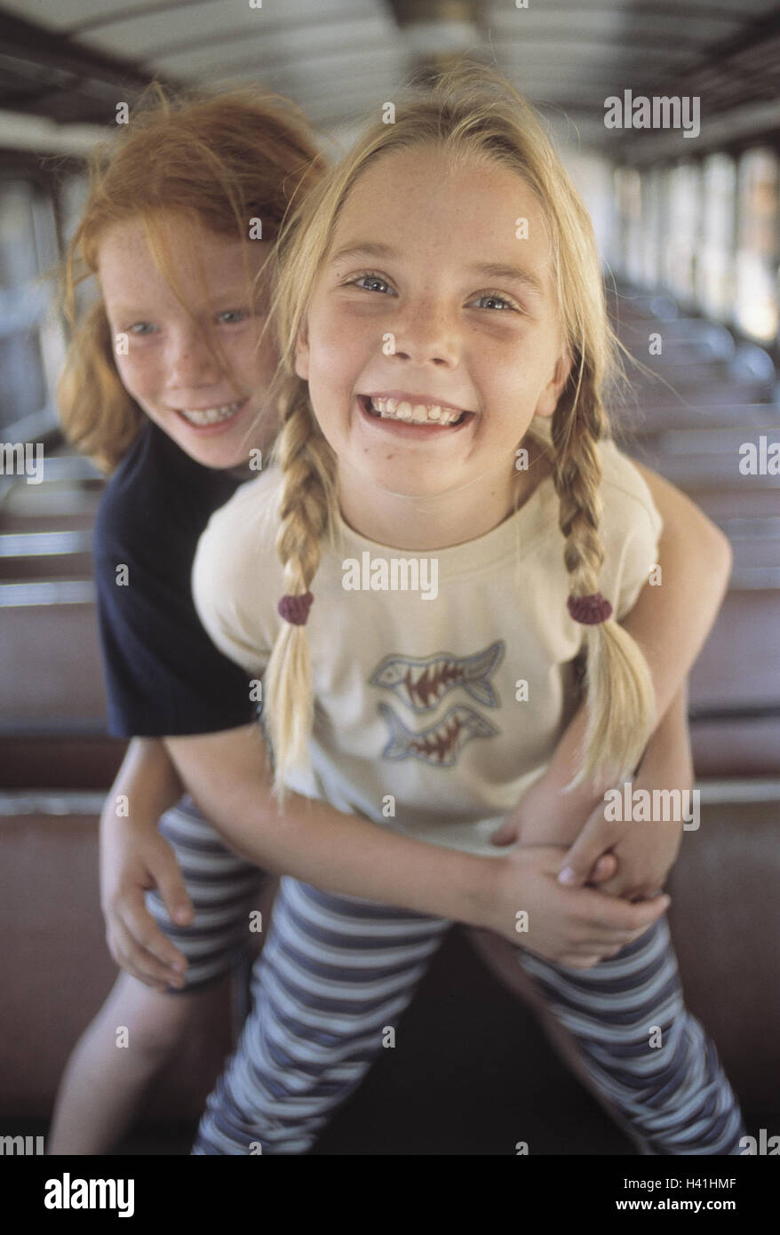Train compartment, girl, happy, embrace, detail, inside, summer, vacation, holidays, leisure time, childhood, children, 9 years, fun, excursion, travel, train travel, train journey, trajectory, railway car, carriage, laugh, amuse funnily, joy, happy, expr Stock Photo