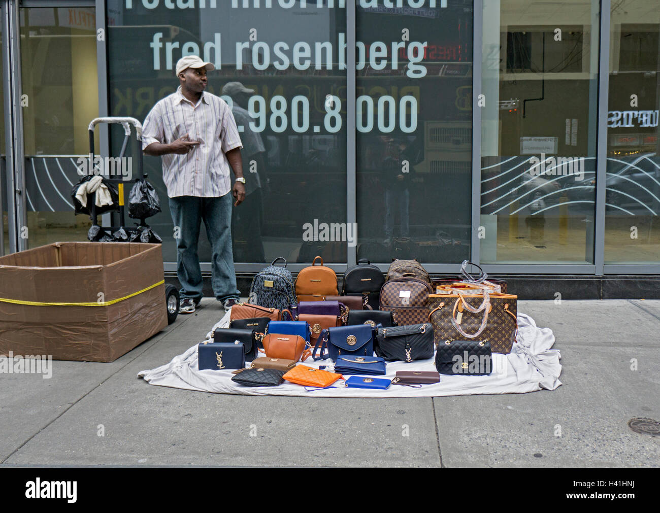 An African American man selling knock off pocketbooks that look like expensive name brands. In Times Square, New York City. Stock Photo