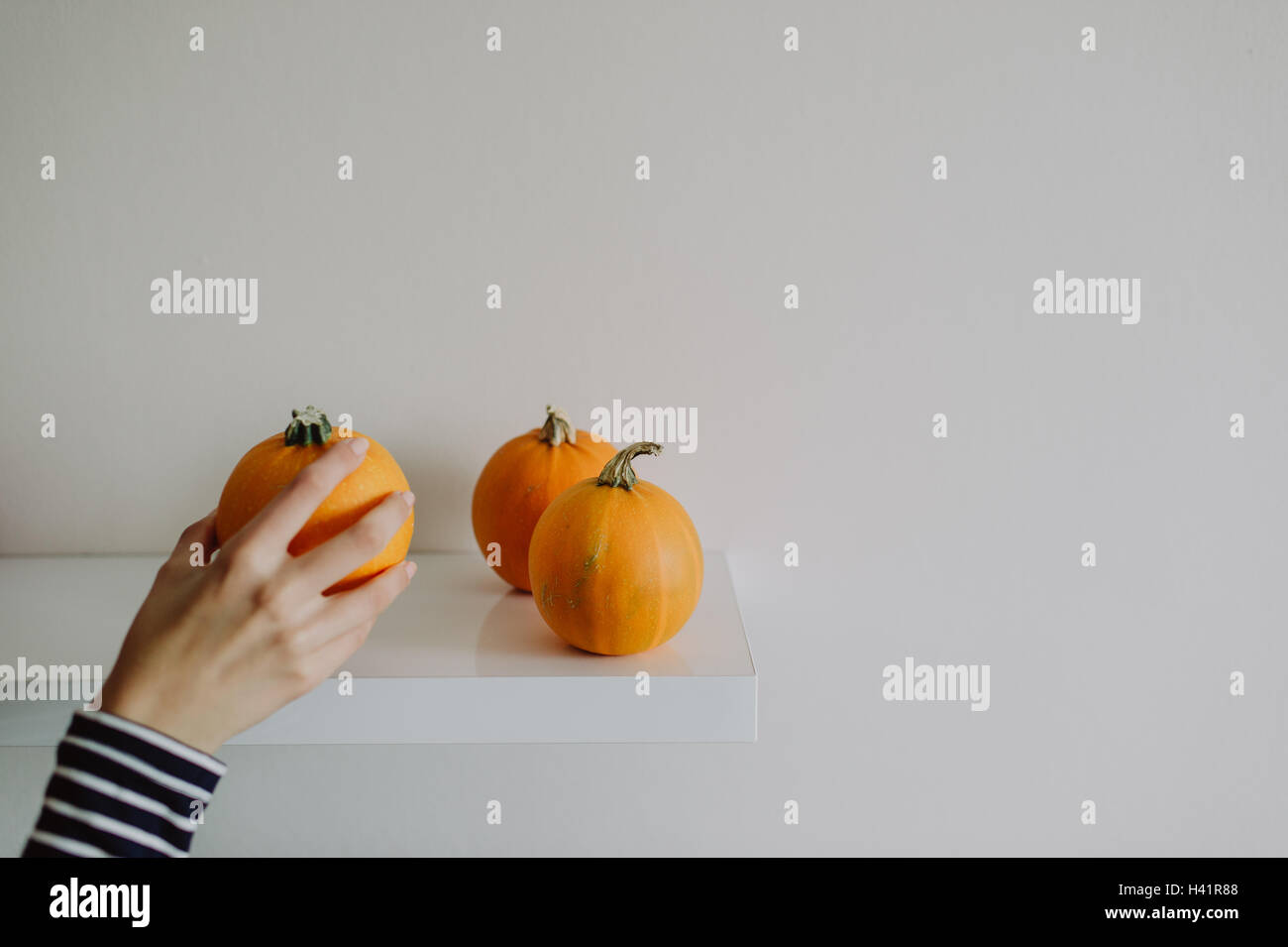 Woman putting pumpkins on a shelf Stock Photo